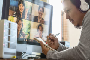 Remote worker in a video call writing in a notebook